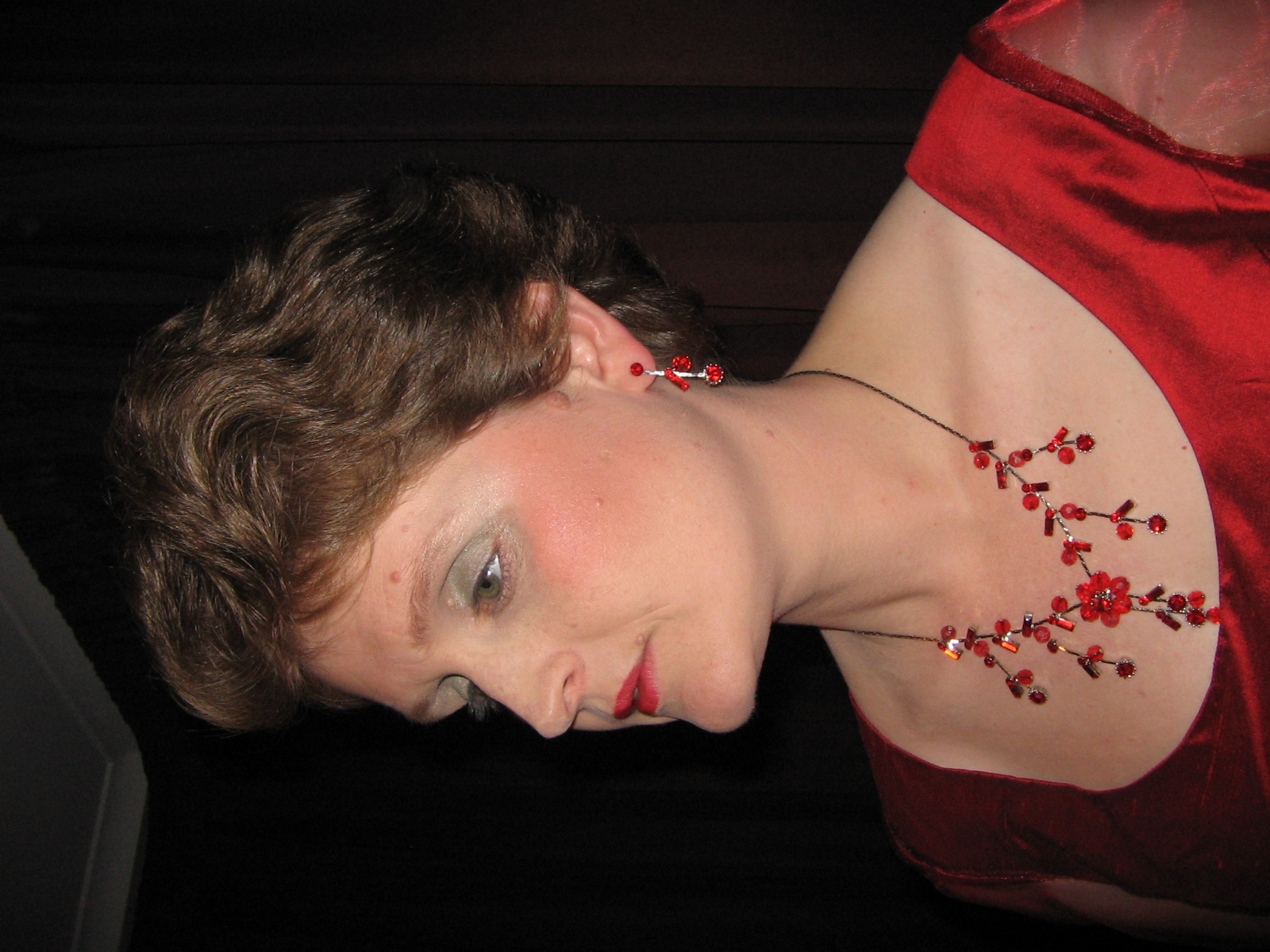 Lisette Wesseling in profile wearing an elegant red gown with matching red beaded jewelry, styled for a performance